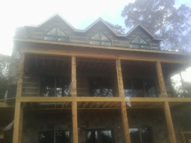 Dormers and porch framing on a large log home under construction — Roof Coating work by our crew in Beverly Hills