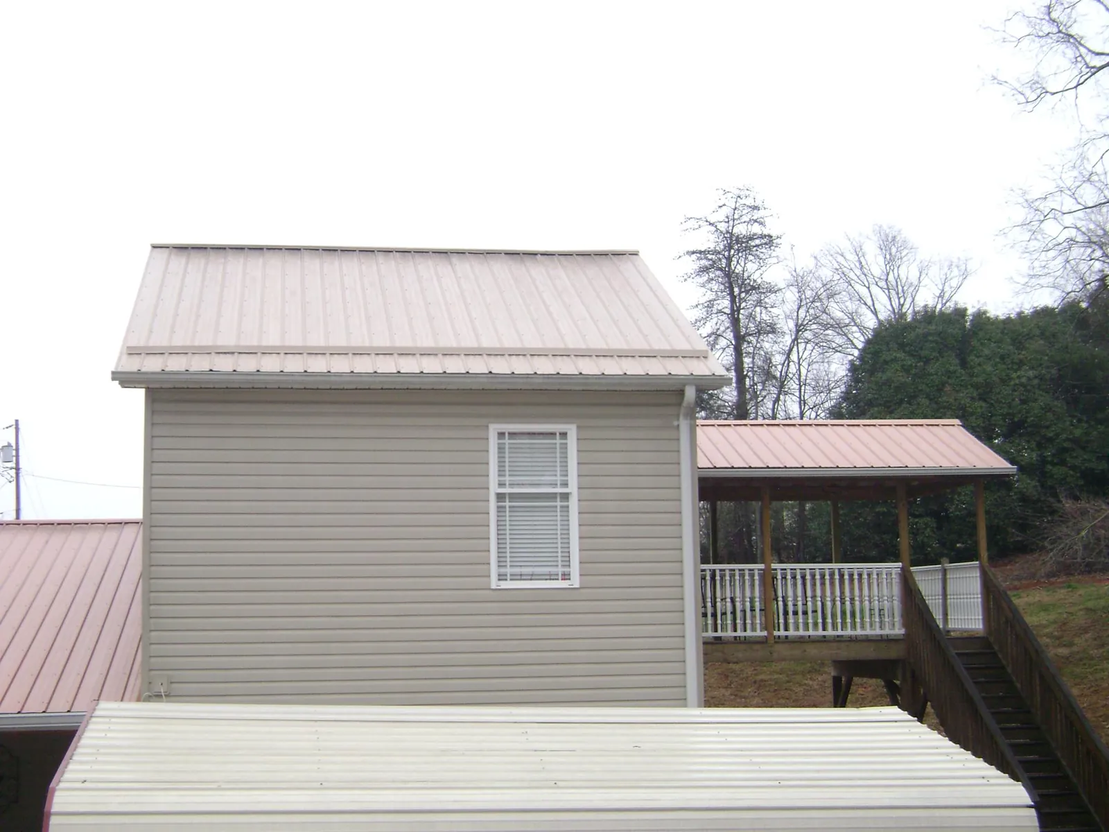 Tan metal roofs on a two story addition and attached porch, from a Roof Replacement job in Beverly Hills