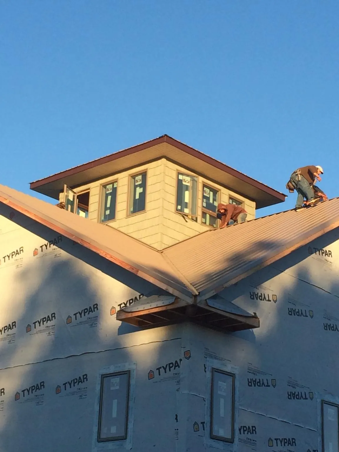 Roofers working around a rooftop cupola on a new metal roof at sunset — Roof Waterproofing in Beverly Hills by Roofing Brothers